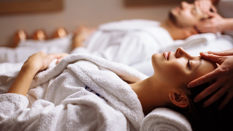 happy young beautiful couple enjoying head massage at the spa